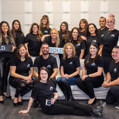 Real estate team in matching black branded t-shirts holding SOLD and open house signs