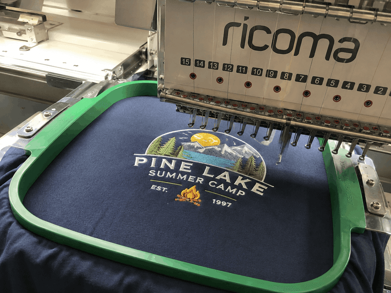 Custom summer camp logo being applied to a branded T-shirt