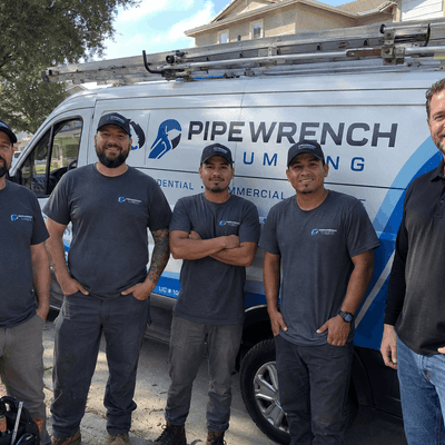 Plumbing company team wearing coordinated custom T-shirts beside a service van