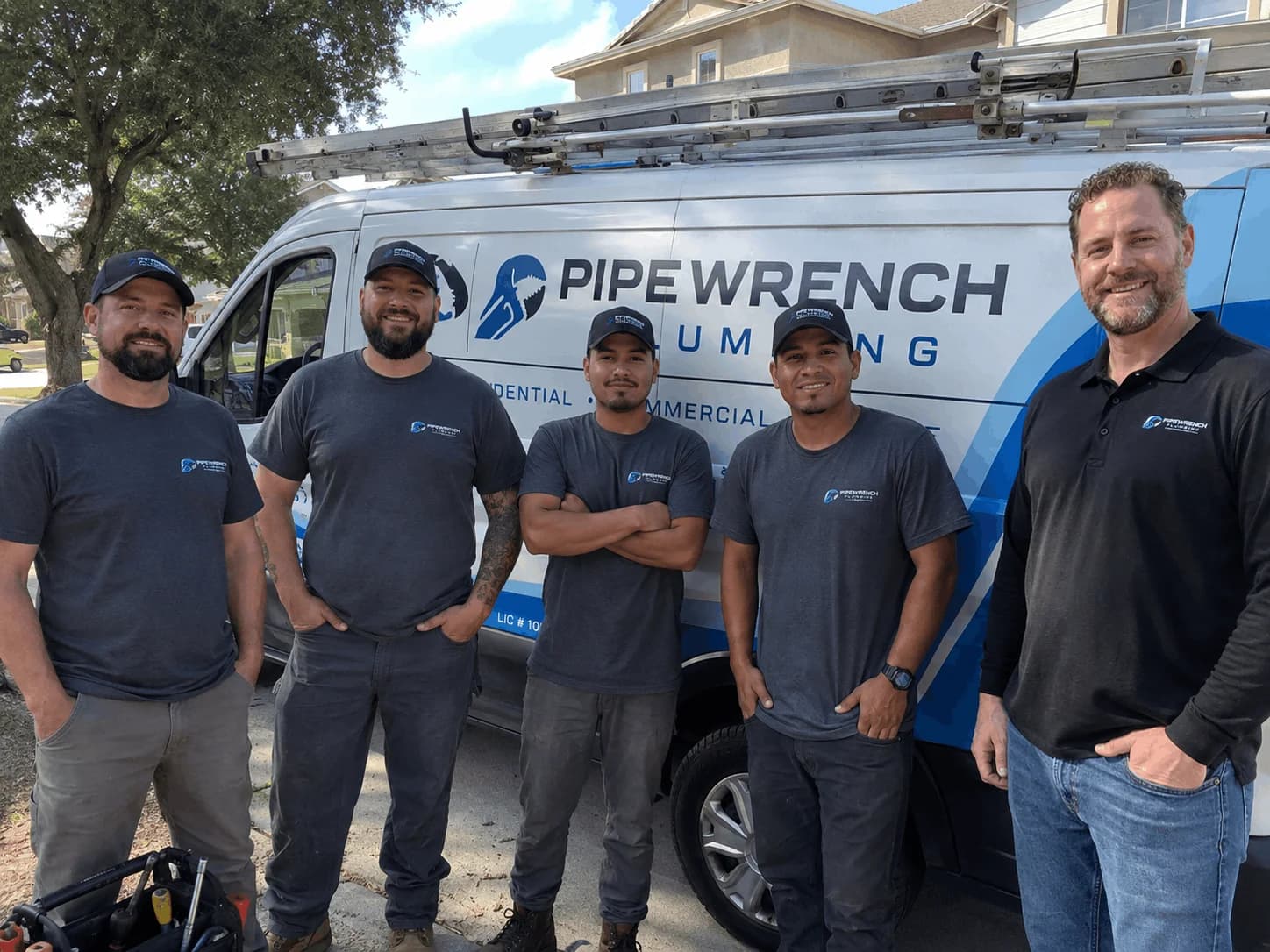 Plumbing company team wearing coordinated custom T-shirts beside a service van