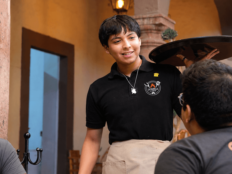 Restaurant server wearing a custom branded shirt while providing customer service in a professional dining environment.