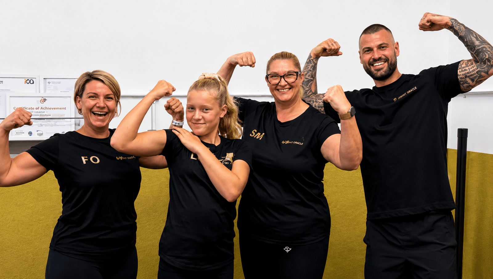 Group of gym members posing and flexing muscles after a strength training workout in a fitness studio.